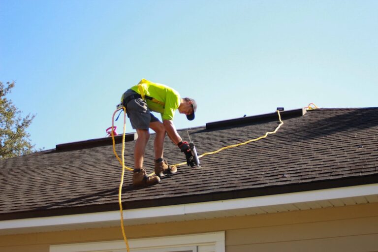 A person using binoculars to inspect an asphalt shingle roof after a storm, with damaged shingles visible.