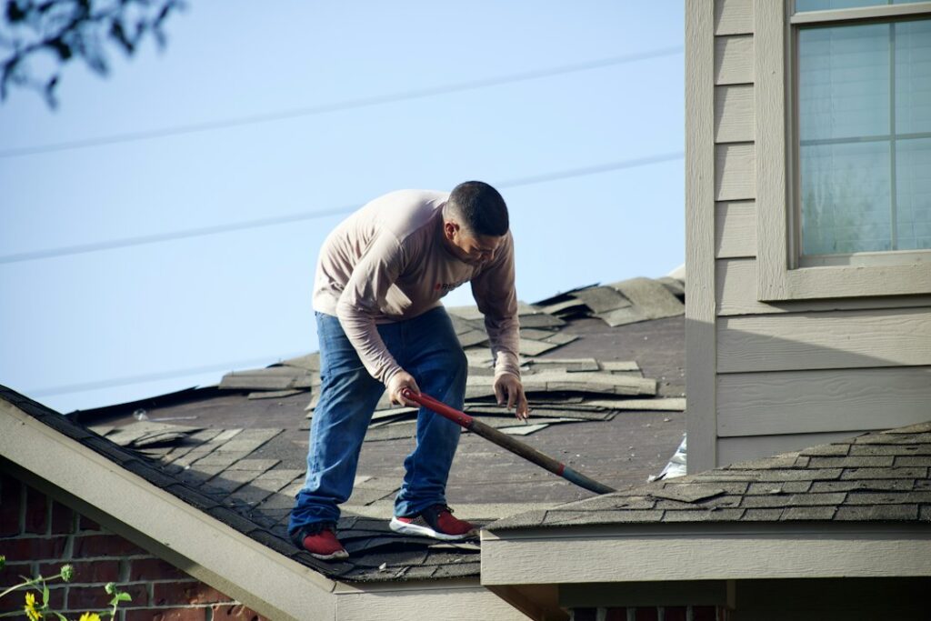 Homeowner reviews roof damage photos and insurance documents at a kitchen table after a storm.