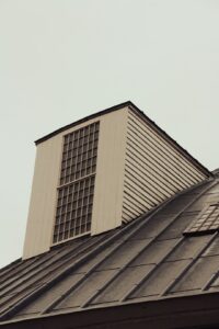 Attic with visible insulation, soffit vents, roof framing, and airflow moving toward a ridge vent.